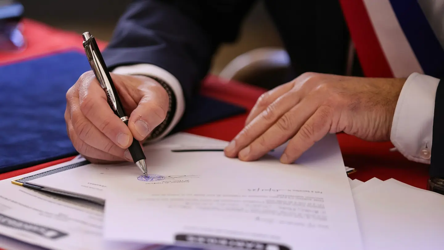 A person signing a printed agreement with a pen